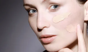 Makeup artist blending liquid foundation on a model's face, illustrating professional application techniques.